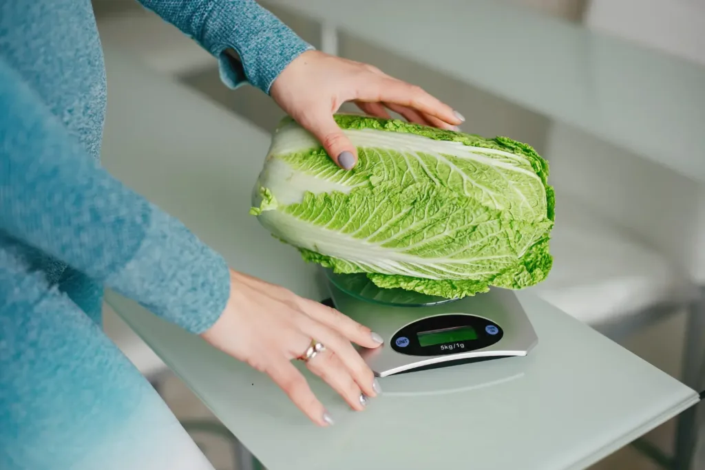 Digital kitchen scale weighing salt and vegetables for precise fermentation ratios